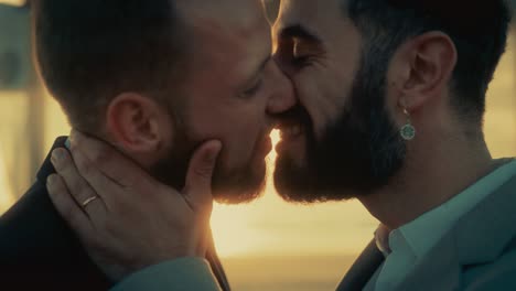 close up portrait of handsome gay couple kiss at outdoors wedding ceremony venue near the sea. two happy men in love share their vows and get married. lgbtq relationship goals.