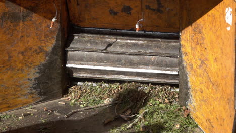 rake pushes lawn debris into mouth of wood chipper in slow-motion