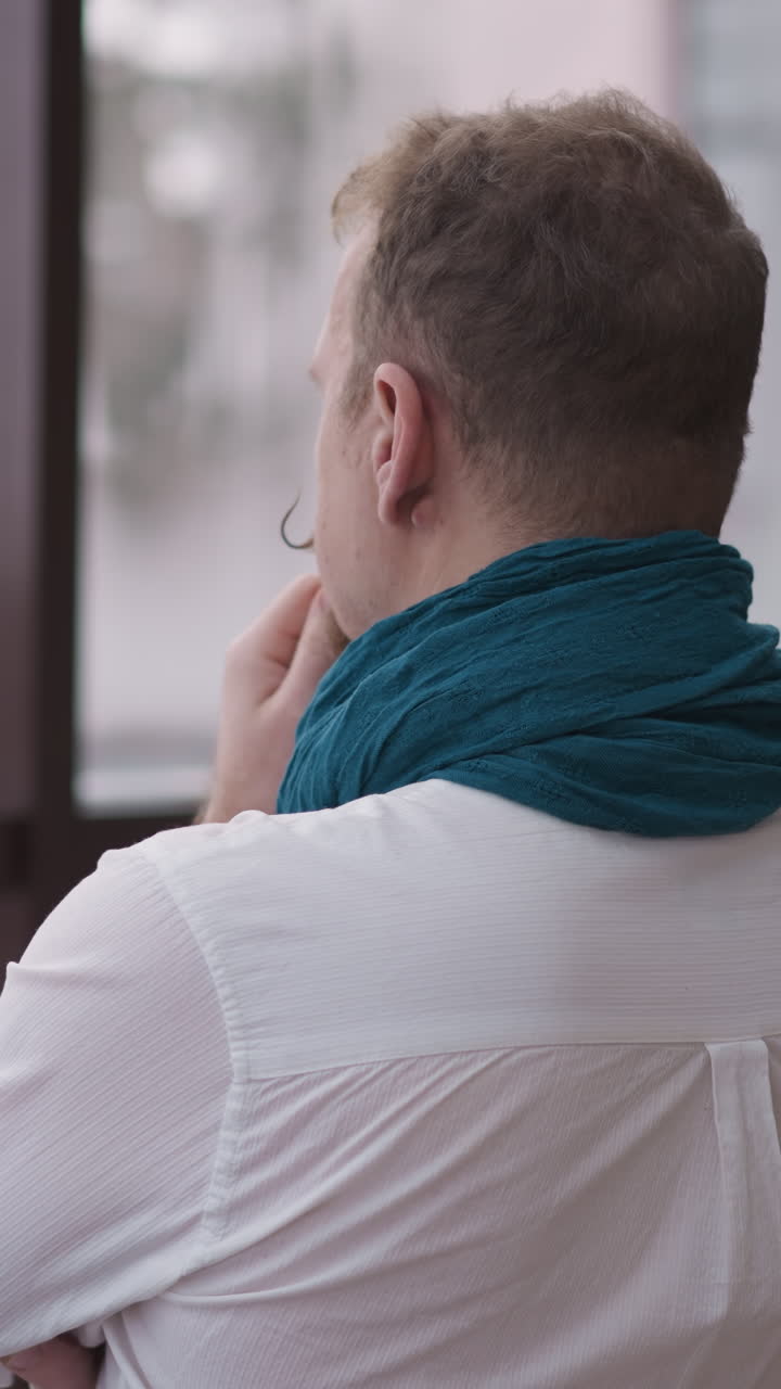 el hombre con la bufanda mira el paisaje invernal. el hombre vuelve la atención a resolver problemas con consideración reflexiva cerca de la ventana en casa. aislamiento pacífico