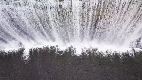 bird's eye drone view of a wide waterfall with a large drop on north island, new zealand