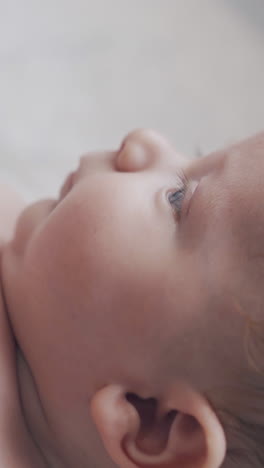 cute newborn son with short fair hair and adorable plump cheeks lies on changing table and moves body extreme close view