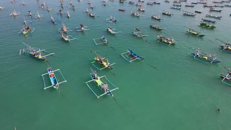 aerial flight over indonesian traditional juking boats bobing on turquoise transparent waves near a tropical island of bali