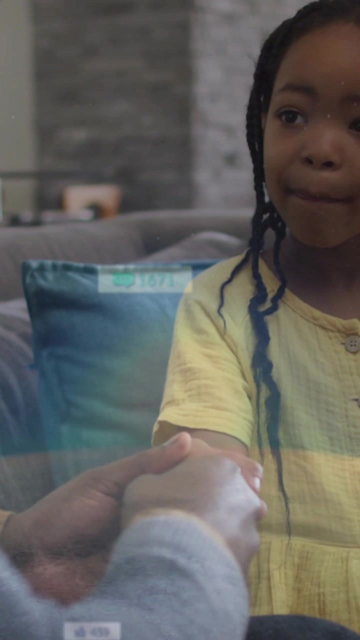 Video verticale: Assistente che si protende e tiene il polso di un bambino, attivando un'interfaccia utente di scansione della salute sul divano.