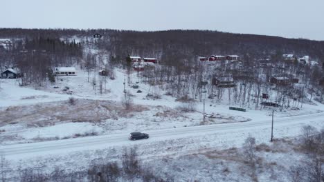 car travelling through desolate winter frozen landscape - low angle aerial side tracking shot