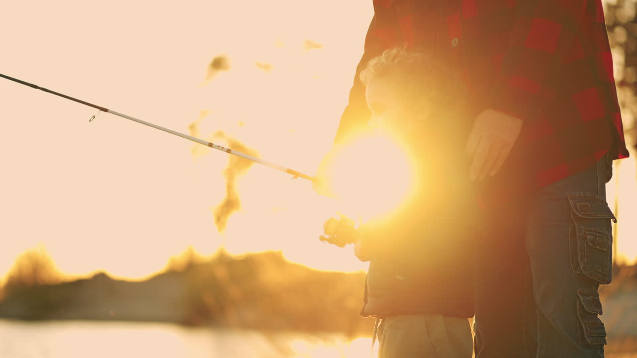 un bambino carino sta catturando pesce con la verga un ragazzino felice e il padre o il nonno sulla riva di un fiume o di un lago