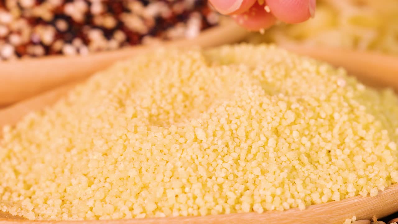 Close-up of hands sifting through couscous grains in warm lighting, highlighting texture and detail