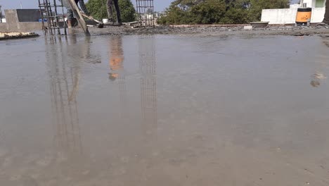 workers pouring concrete reinforcement into a floor metallic structure base low angle, construction workers are adjusting the surface of the cement floor by plastering equipment