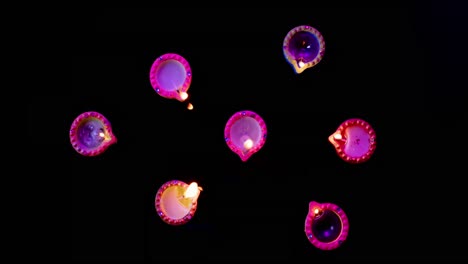 Close-up-of-burning-colourful-candles-celebrating-diwali-on-black-background