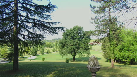 aerial drone footage flying through tall trees in a beautiful garden over an old feature wall, italy