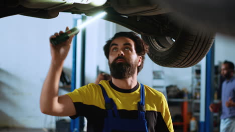 Serviceman-inspects-car-on-overhead-lift