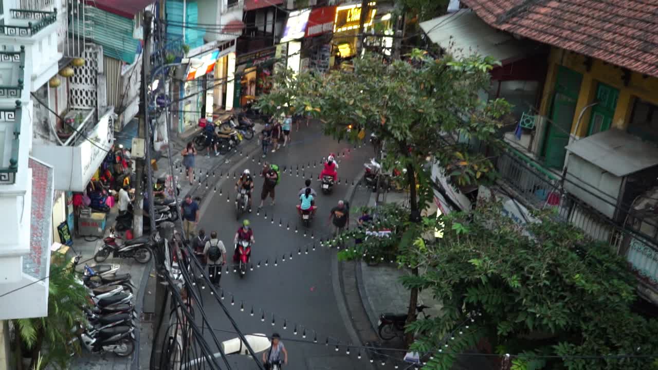 People riding a scooter through the streets of busy hanoi city in Vietnam. Zoom out