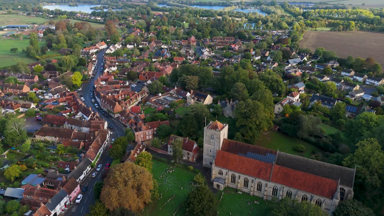 Aerial drone shot rising from 40m above Dorchester Abbey, Oxfordshire, England. The drone slowly ascends while turning right, revealing the village of Dorchester on Thames framed beyond the abbey roof