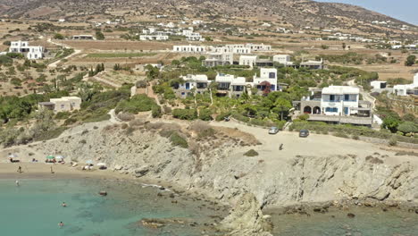 paros greece aerial v4 panning shot capturing the greek style whitewashed sea view holiday homes on rocky clifftop at paralia lolantonis beach - september 2021