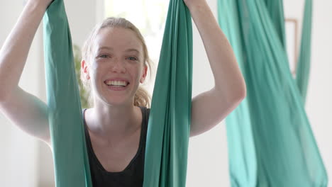 portrait of happy caucasian fitness teenage girl on gymnastic sash in white room, slow motion