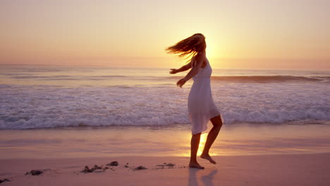 Free-happy-woman-spinning-arms-outstretched-enjoying-nature-dancing-on-beach-at-sunset-slow-motion-RED-DRAGON