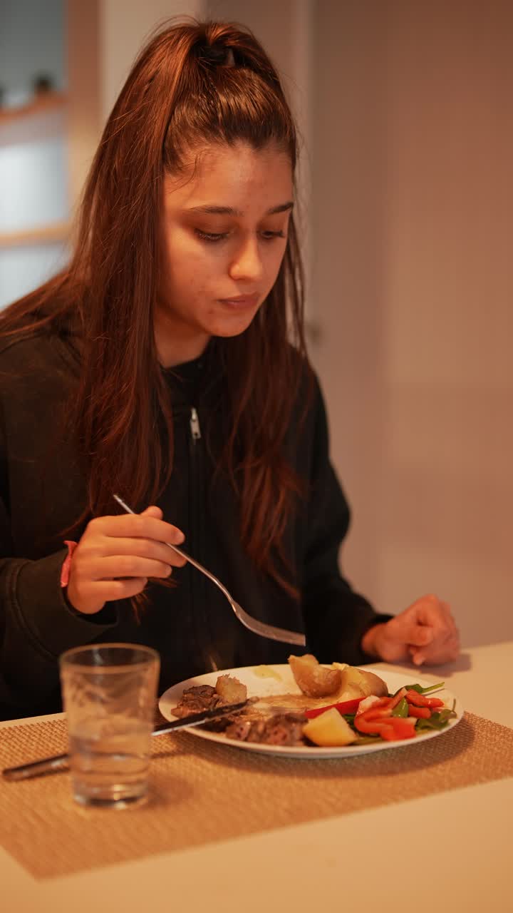 una adolescente comiendo la cena.