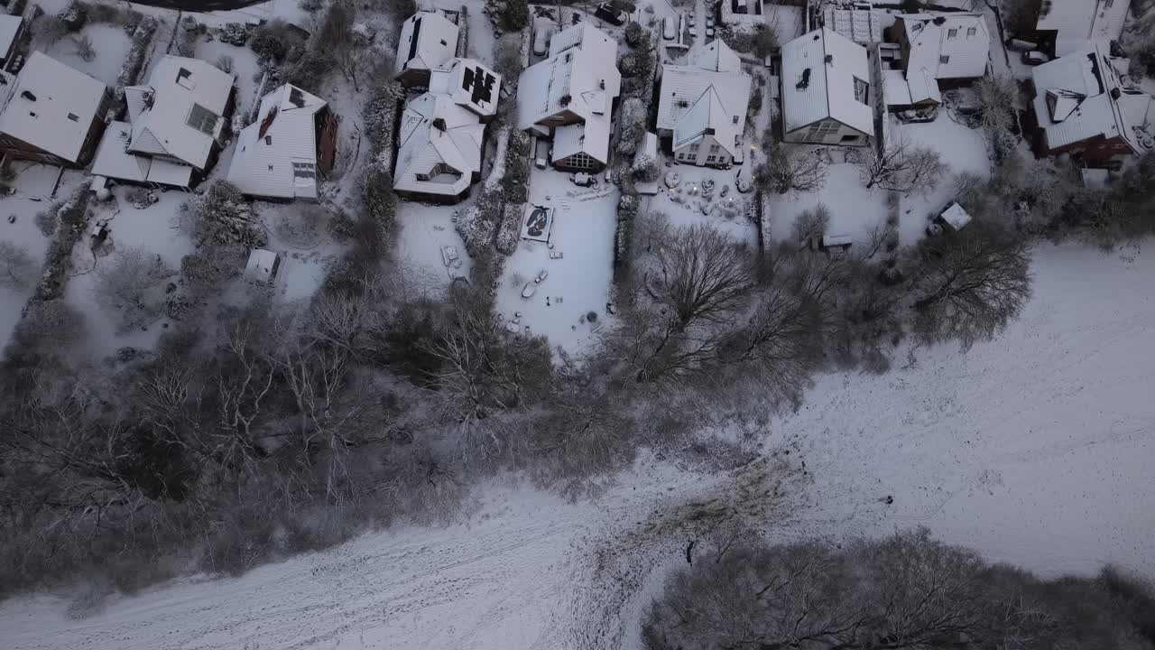 Case unifamiliari innevate di un quartiere suburbano americano dopo una tempesta di neve serale. Sorvolo aereo dall'alto verso il basso. Alberi spogli e gelidi nel quartiere rurale della città. Meraviglie invernali completamente bianche