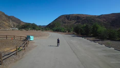imágenes aéreas de un hombre que conduce un monociclo eléctrico por una carretera en california 3