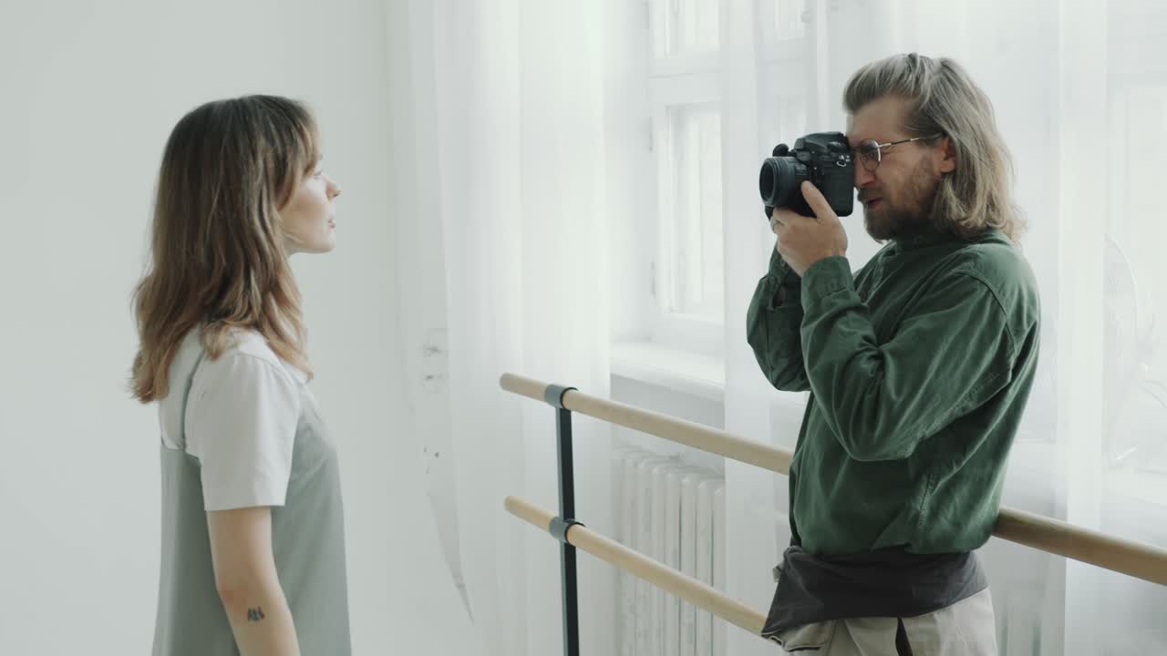 Fotografo che scatta un primo piano di una giovane donna in uno studio ben illuminato.
