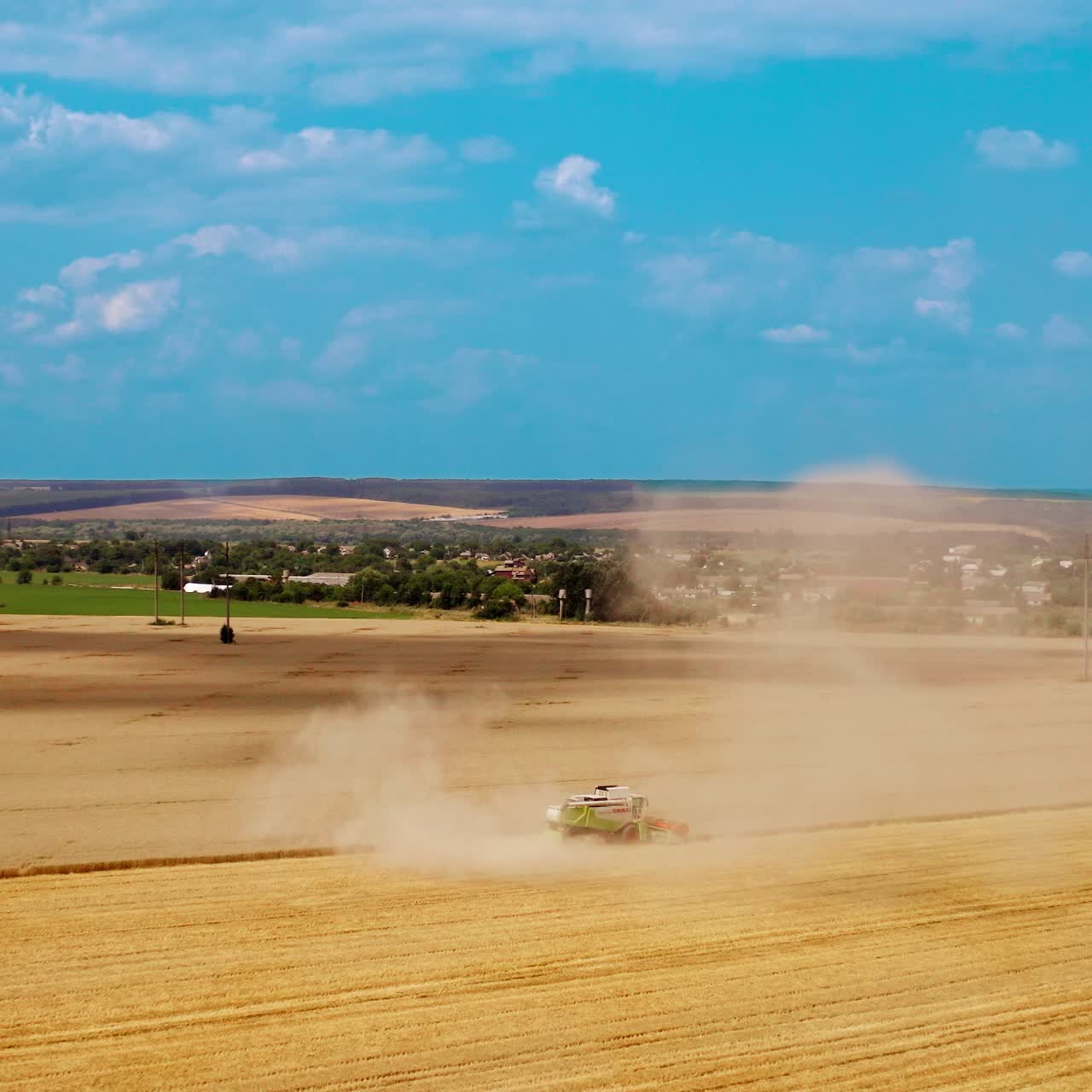 Harvesting ripe crop in farmland. Large dust from combine harvester on field during agronomy works in rural place. Aerial view