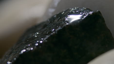 throwing water on hot stones in the sauna stove, slow motion close up of water splashing and evaporating into steam, heating the sauna