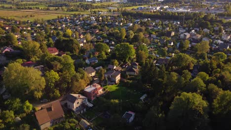 drone revealing suburban town through dense trees in ogre, latvia