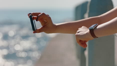 manos cercanas mujer tomando una foto usando un teléfono inteligente de la hermosa playa compartiendo vacaciones de verano en las redes sociales