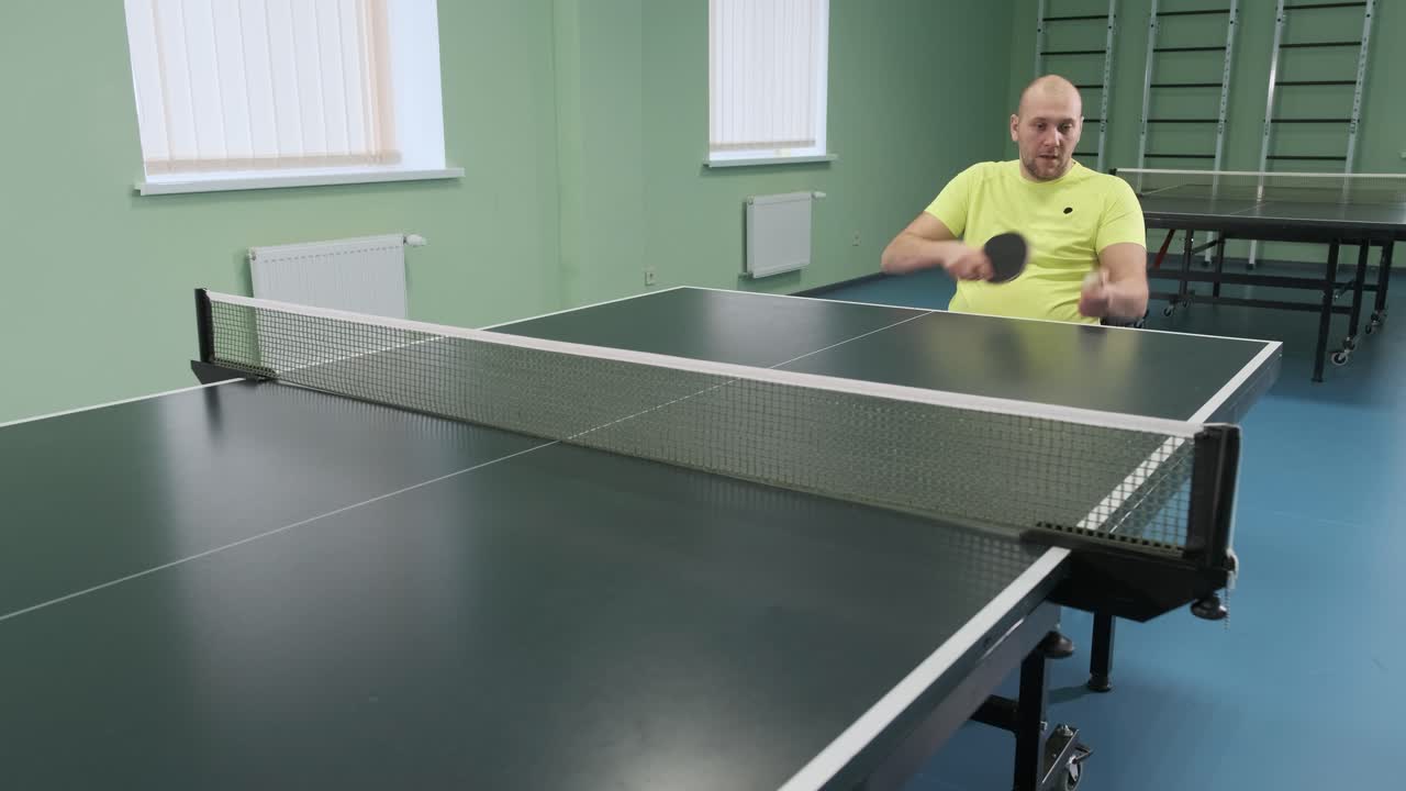 un hombre en silla de ruedas juega al ping-pong. personas con discapacidad juegan al tenis de mesa. rehabilitación de discapacitados. deporte.