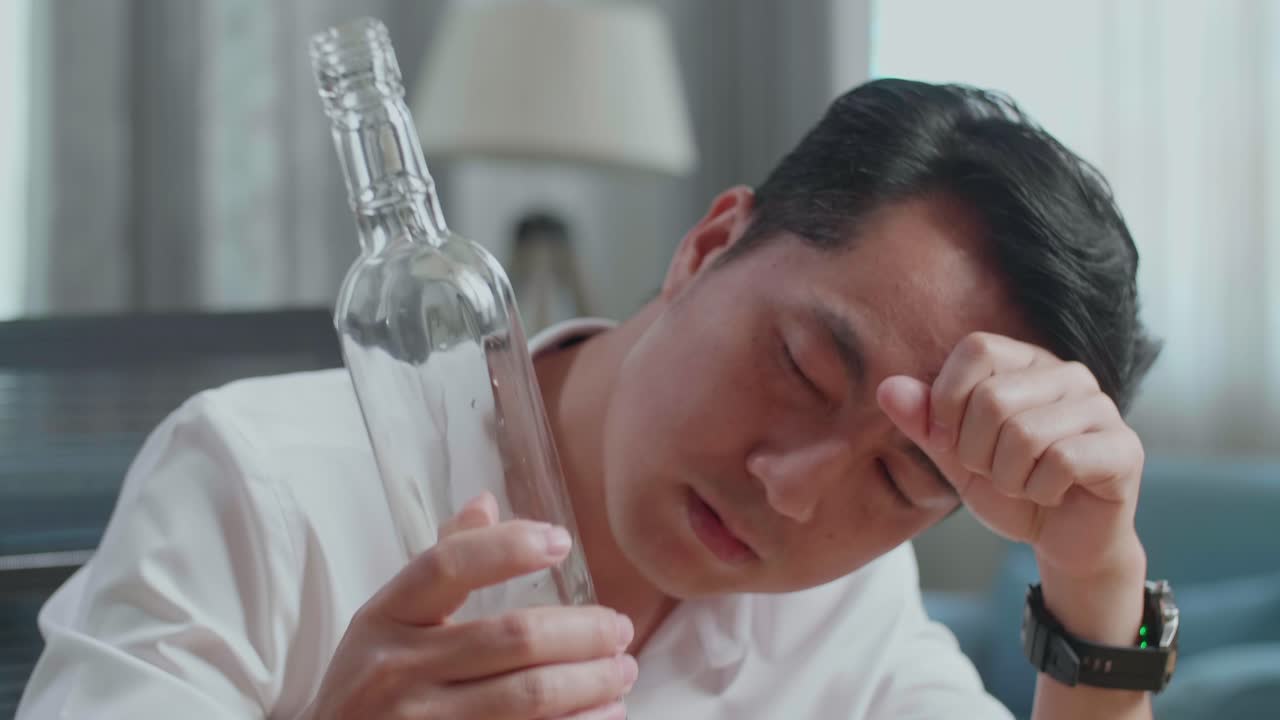 술에 취한 아시아인 남자가 집에서 보드카를 마시고 있는 장면