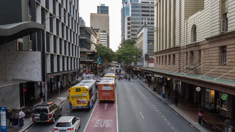 timelapse shot of busy road traffics, looking straight at adelaide street with buses and cars driving across and people rushing at central business district, rapid population growth of brisbane city