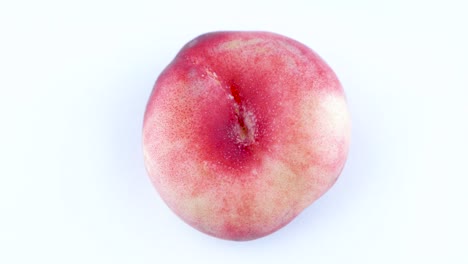 top view from above of man hand placing one doughnut flat peach one the turntable isolated on the white background. close-up. macro.