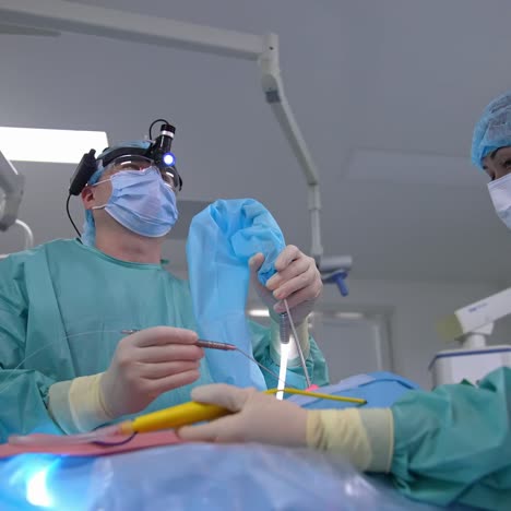 nurse assistant passes the surgery instruments to the surgeon. professional performing the operation in modern clinic. view from below