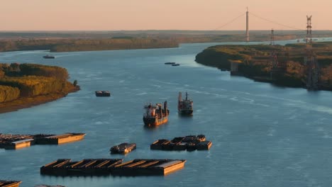 aerial tracking close up shot of anchored ships on a big blue river, suspended bridge in the brackground, clear sunny day, 4k50fps