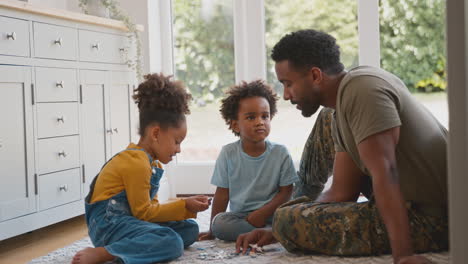 army father in uniform home on leave with children doing jigsaw puzzle together