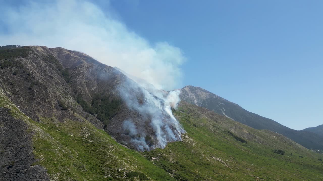 Mountain burning from fires causing emergency and releasing smoke and ash in the air