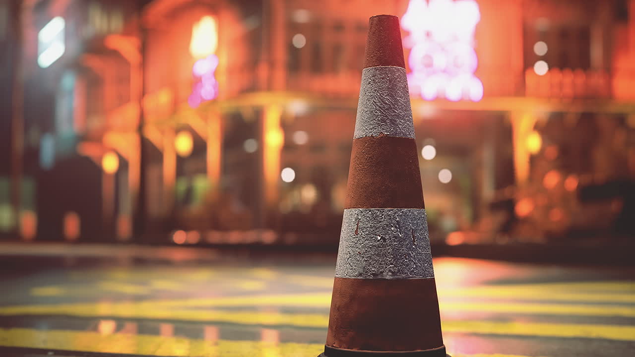 Traffic cone illuminated by neon lights at night in urban setting