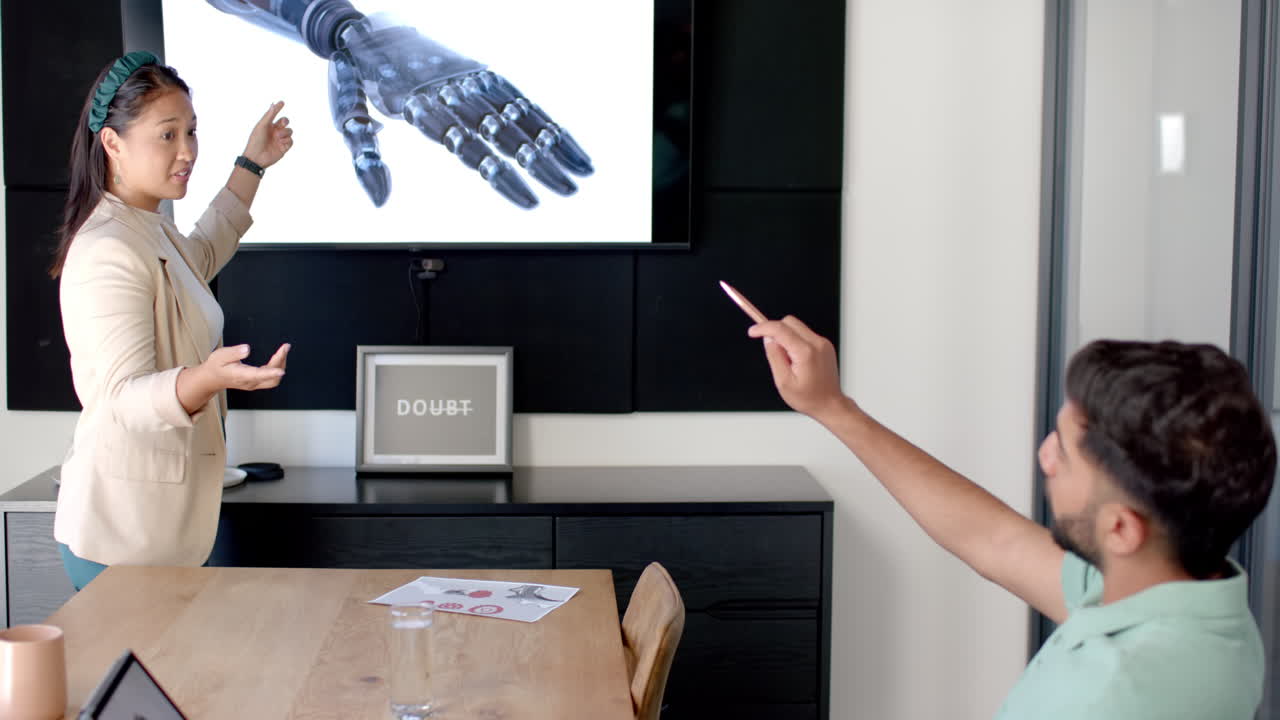 Presenting robotic hand design, woman pointing at screen while man holding pen