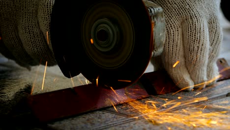 hands of mechanic using electric grinder to cutting the steel with fire light flicker