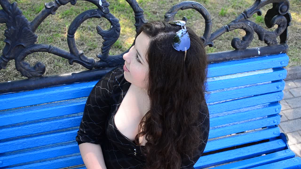 La ragazza con un sorriso sul volto. La giovane ragazza attraente su una panchina