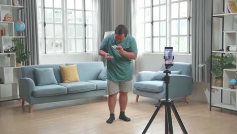 asian man blogger shoots video content for social networks by smartphone camera, magician with playing cards