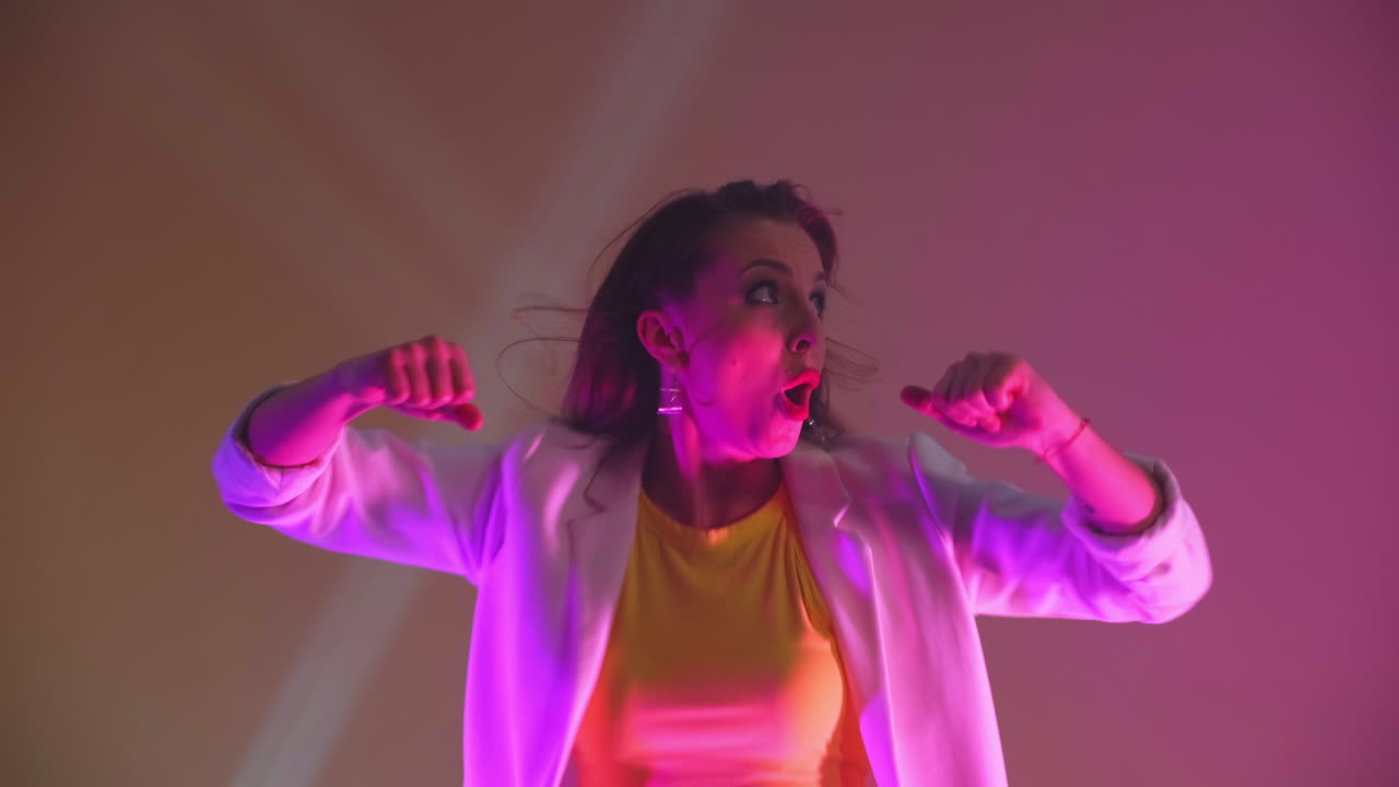 una donna energica e positiva balla con gioia su uno sfondo giallo in studio e urla guardando la telecamera. successo e gioia. il concetto di felicità.