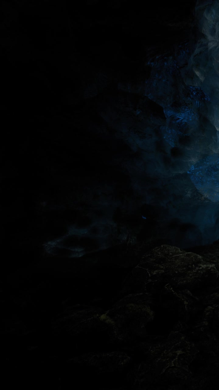 Light shines through the cave entrance in the dark on a cloudy evening