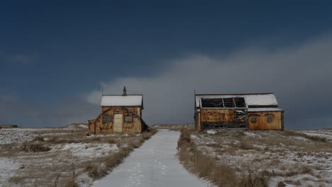 12 second timelapse of cloud cover moving fast above an abandoned farm covered in snow.