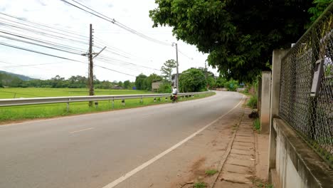 a solo asian woman long distance cyclist and backpacker dressed in athletic clothes riding through nan province on her foldable bicycle on the left side of the road when a jeep overtakes her, thailand