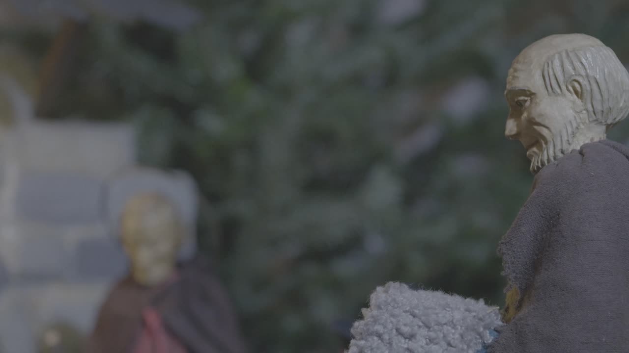 un anciano pastor se para frente al establo en un belén