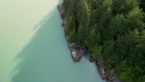 aerial topdown pan of howe sound ocean coastline and trees stawamus chief reveal, squamish, bc, canada