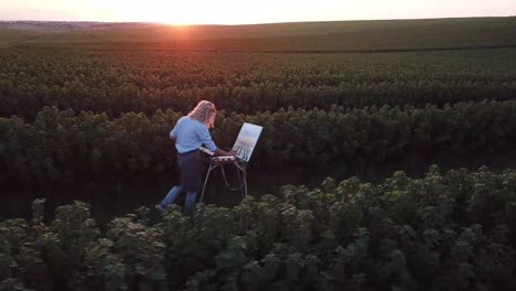 a professional artist paints a picture with oil paints - a professional artist paints a picture with oil paints. beautiful field at sunset