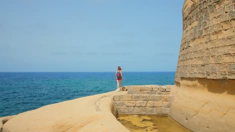 backpacker woman hiking and visiting the ruins of qolla l-bajda on the island of gozo, malta