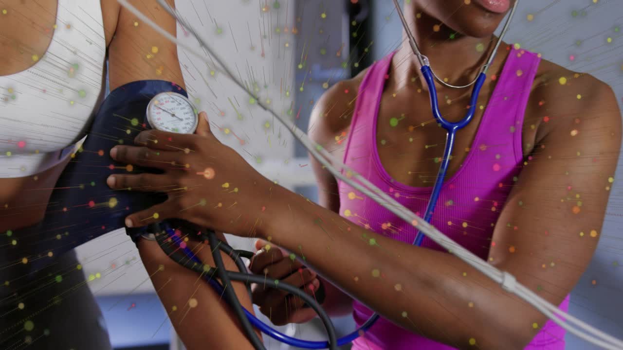 Trainer in pink tank placing cuff, taking BP, watching gauge amid speckle overlay for health