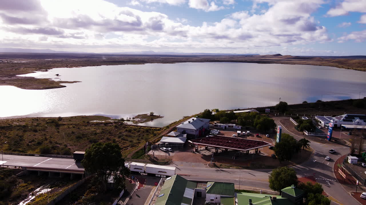 Freight trucks on highway entering and exiting Beaufort West, view of dam